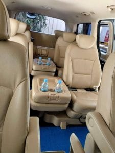 Beige leather seats and cup holders with bottled water inside a private transfer van