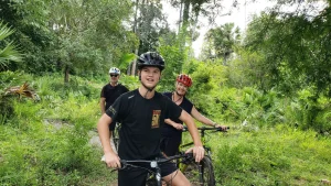 Travelers cycling near Angkor Wat during a private 9-day Cambodia adventure featuring trekking and boating