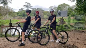 Travelers cycling near Angkor Wat during a private 9-day Cambodia adventure featuring trekking and boating